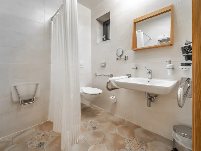Accessible bathroom in Cornelius, NC, featuring a roll-in shower with grab bars, fold-down bench, and curbless entry